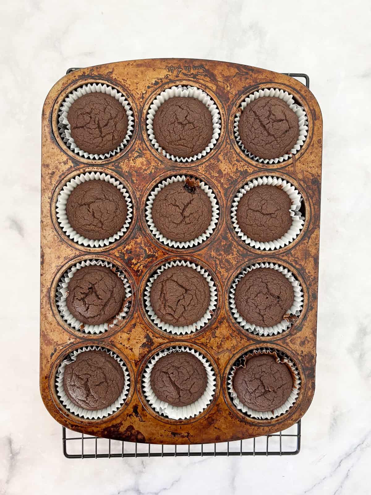 Delicious one-bowl vegan gluten-free chocolate cupcakes are made with oat flour and a handful of simple ingredients. So soft and fluffy! Vegan gluten-free chocolate cupcakes cool in a tin.