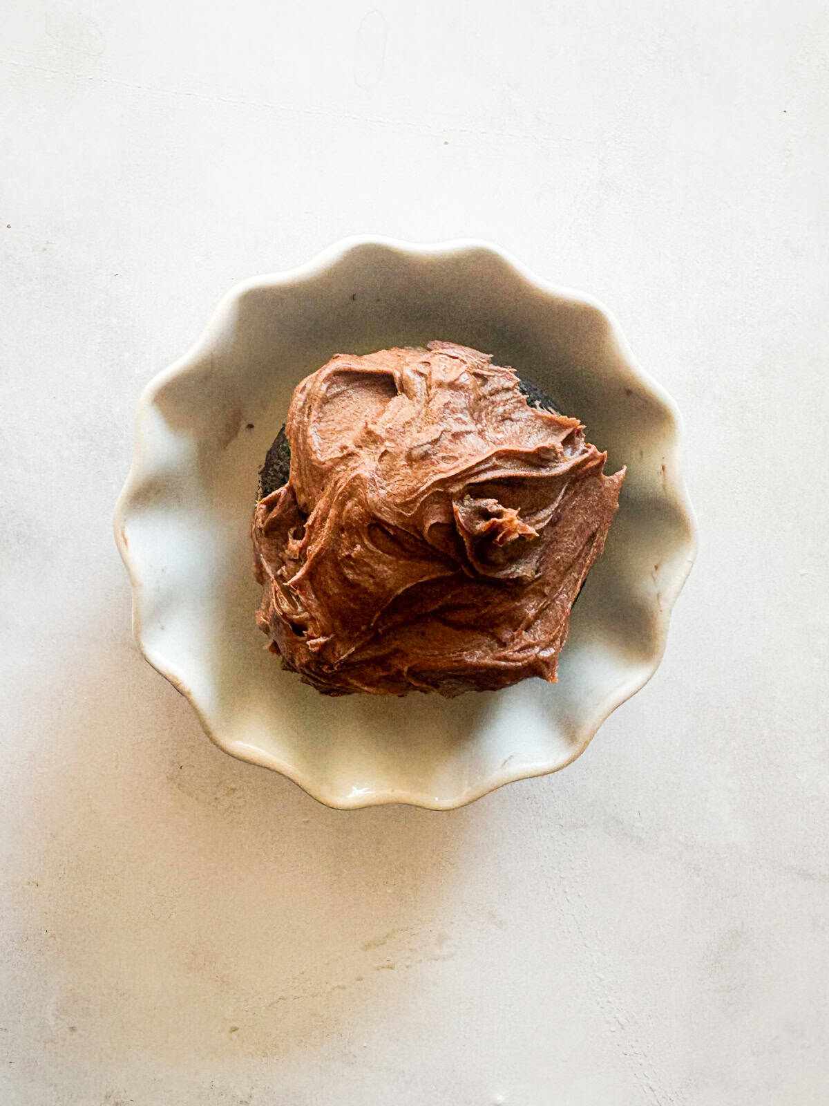 Delicious one-bowl vegan gluten-free chocolate cupcakes are made with oat flour and a handful of simple ingredients. So soft and fluffy! A vegan gluten-free chocolate cupcake on a pretty plate.