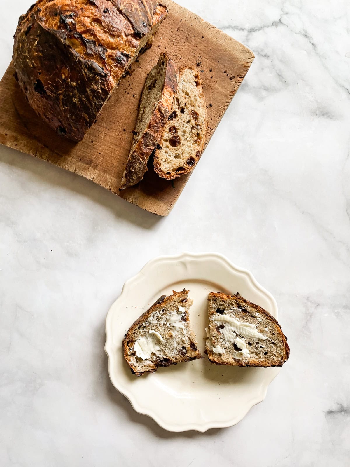 Easy no knead gluten free cinnamon raisin bread benefits from a long overnight rise and a bake in a hot Dutch oven. A loaf of gluten free cinnamon raisin bread on a cutting board and a slice of bread on a plate.