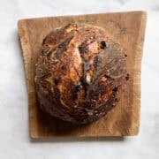 A loaf of gluten free cinnamon raisin bread on a wooden cutting board.