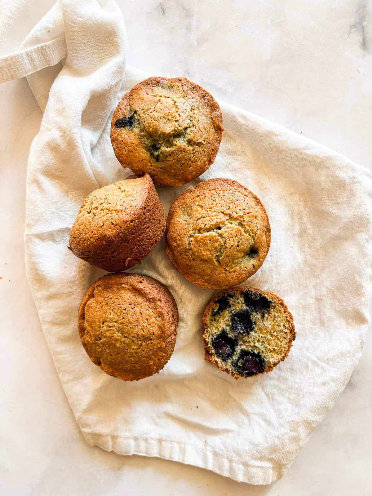 A few gluten free lemon blueberry muffins in a white napkin.