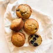 Five gluten free lemon blueberry muffins on a white napkin.