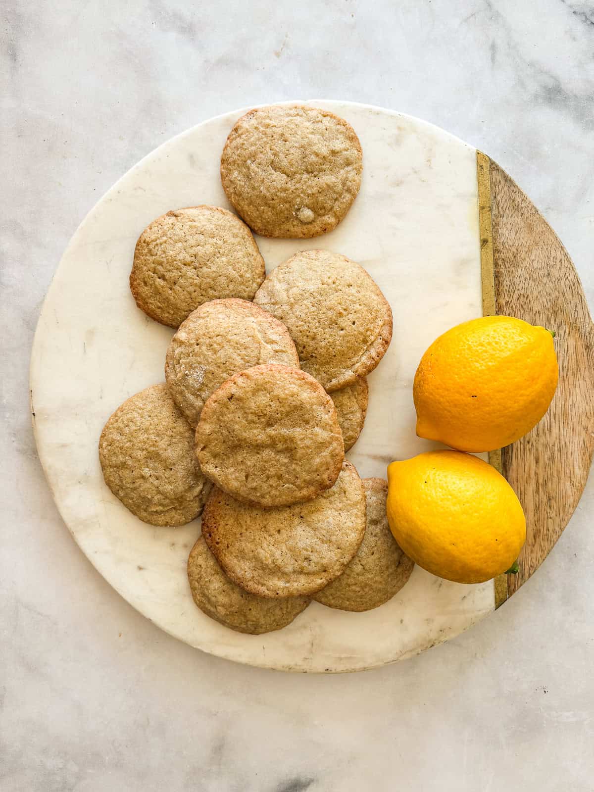 A couple of lemons and a bunch of gluten free lemon cookies on a plate.