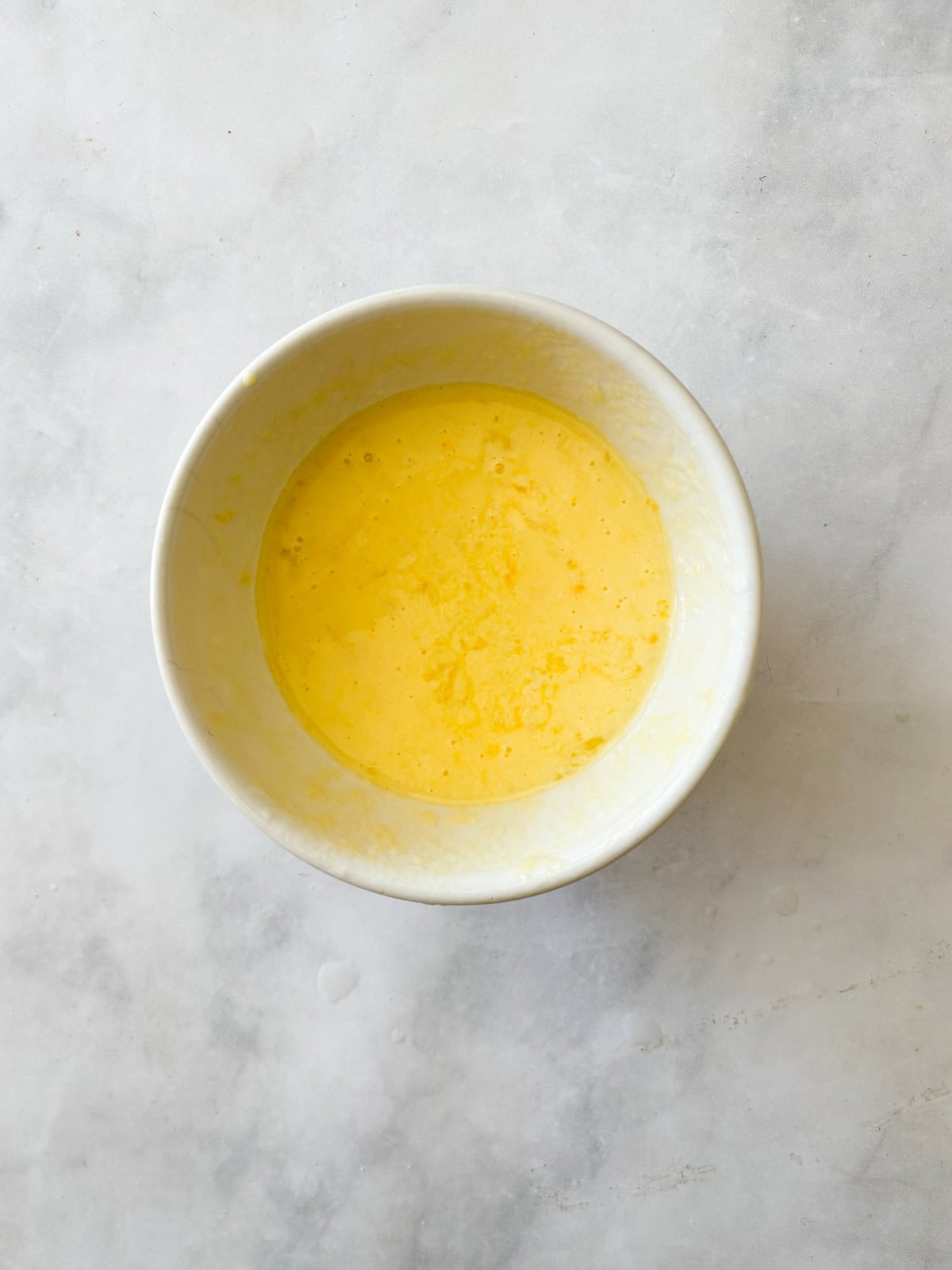 A simple recipe for gluten free lemon scones that tucks lots of fresh lemon zest into a tender, flaky oat flour scone topped with lemon glaze. Eggs and yogurt mixed together to be added to gluten free lemon scones dough.