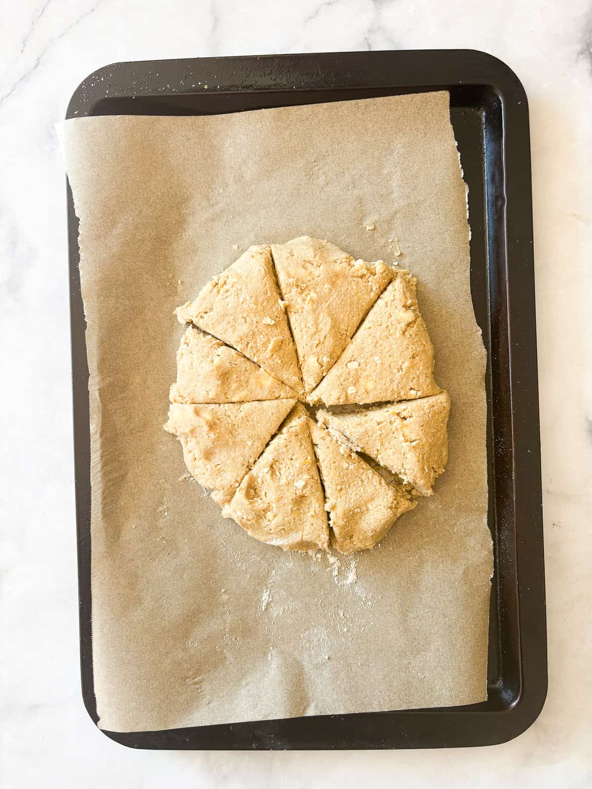 A simple recipe for gluten free lemon scones that tucks lots of fresh lemon zest into a tender, flaky oat flour scone topped with lemon glaze. Gluten free lemon scones dough on a lined baking sheet.