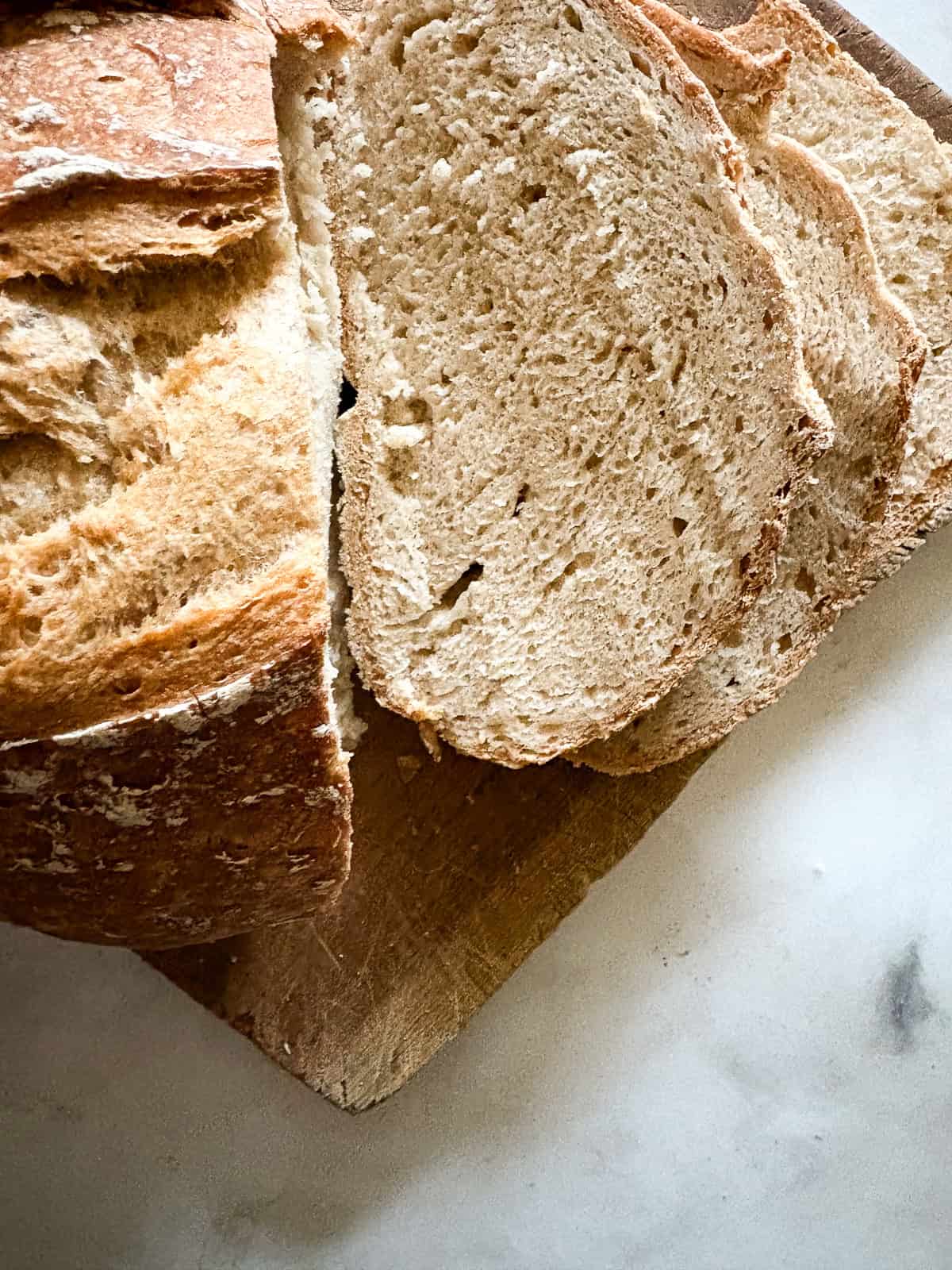 A crusty gluten-free no-knead bread recipe made with 4 simple ingredients. It bakes up perfectly every time and rivals any wheat-based bread! Slices of gluten free no knead bread are cut from the loaf.