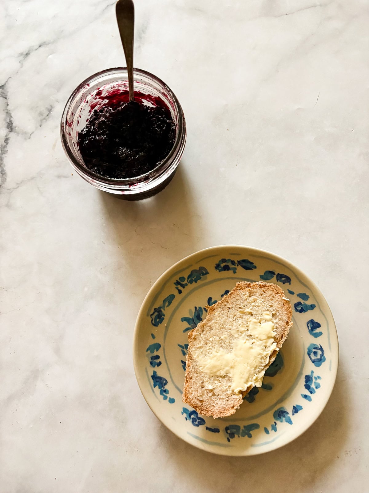 A crusty gluten-free no-knead bread recipe made with 4 simple ingredients. It bakes up perfectly every time and rivals any wheat-based bread! A buttered slice of no knead gluten free bread on a plate with a jar of jam.