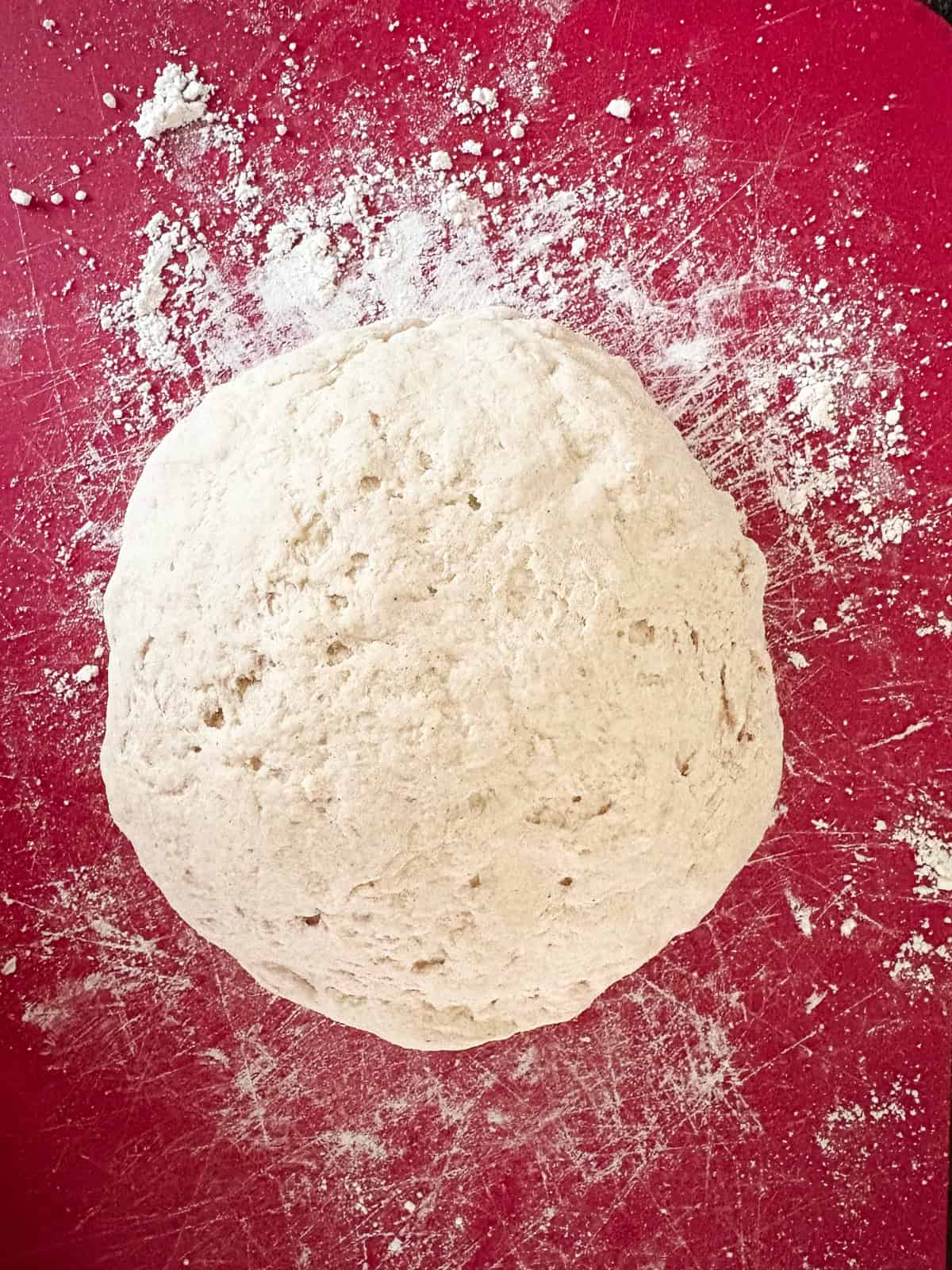 A crusty gluten-free no-knead bread recipe made with 4 simple ingredients. It bakes up perfectly every time and rivals any wheat-based bread! Gluten free no knead bread dough formed into a loaf.