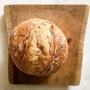 A loaf of gluten free no knead bread on a wooden cutting board.