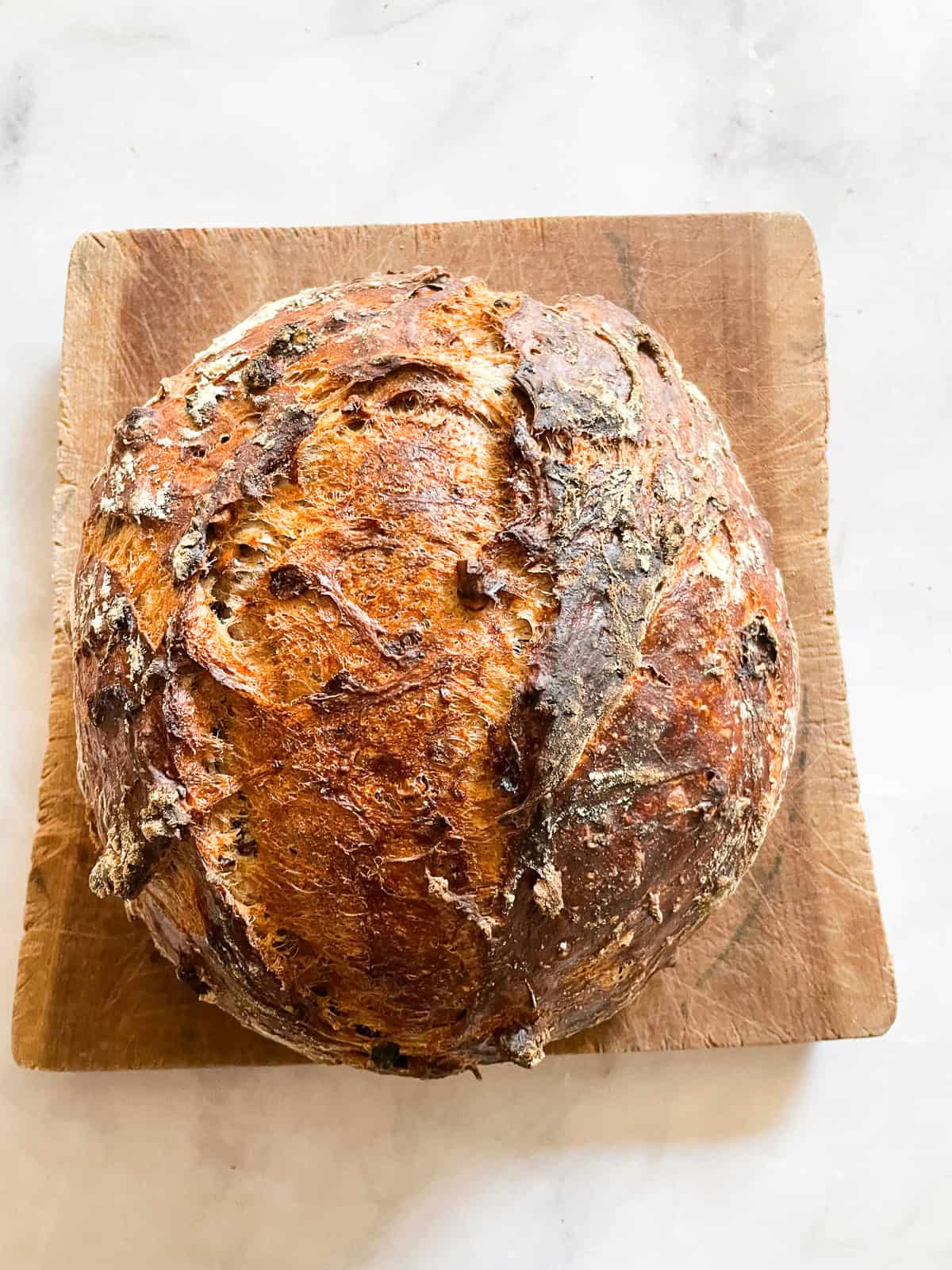 A loaf of gluten free no knead cranberry walnut bread on a cutting board.