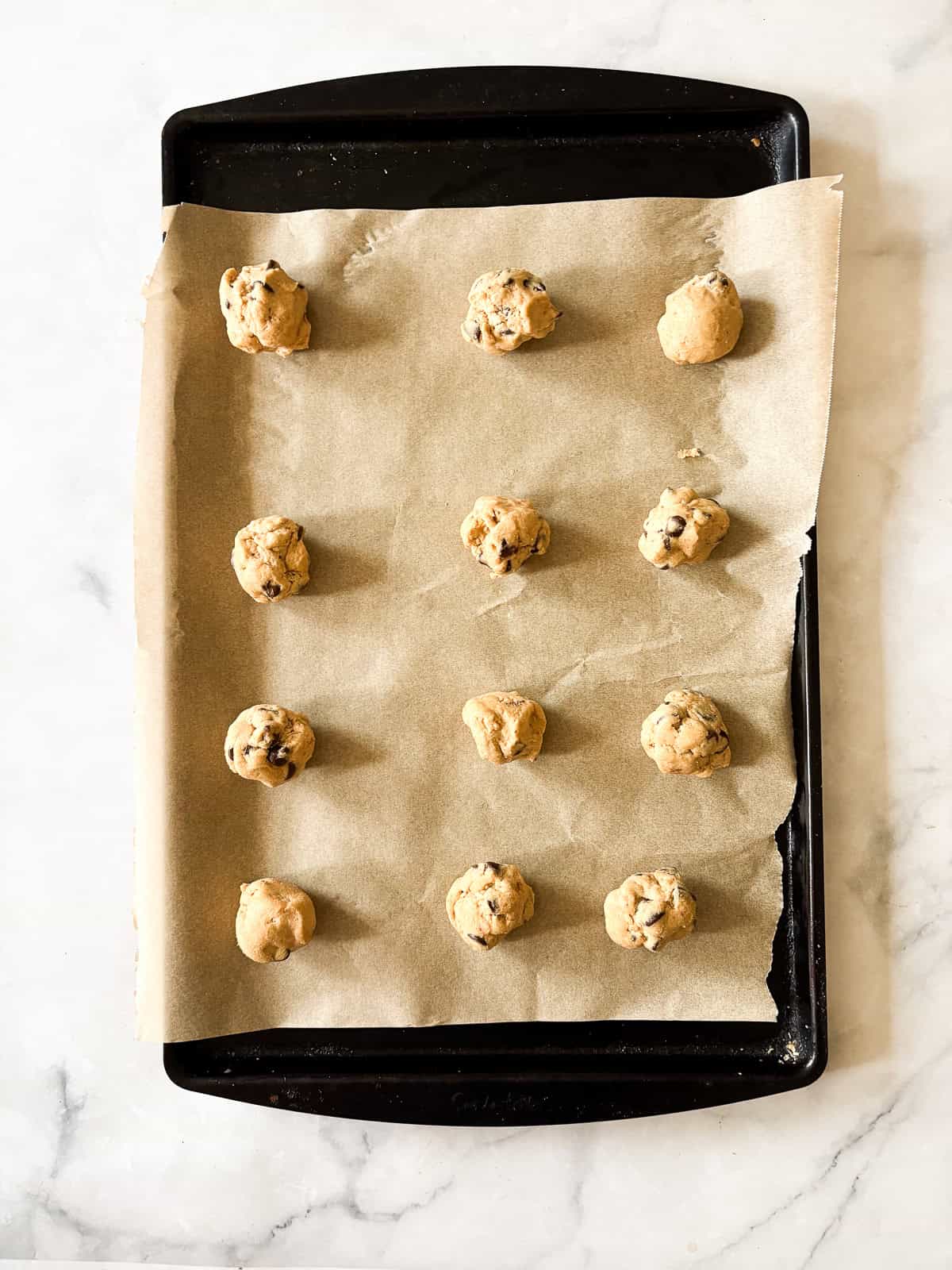Chewy and irresistible, these gluten-free peanut butter chocolate chip cookies are made with plenty of creamy pb plus lots of chocolate! Gluten free peanut butter chocolate chip cookies dough balls are arranged on a baking sheet.