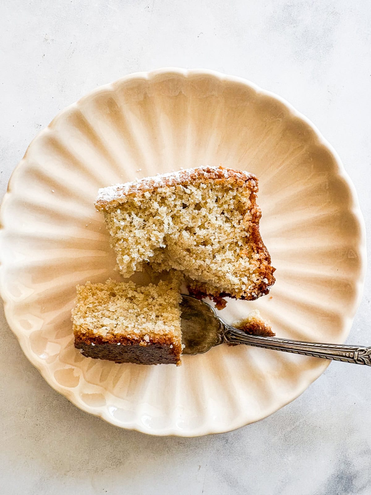 Whip up this one-bowl gluten free snack cake and enjoy with a cup of coffee, or have it waiting on the counter for when the kids come home. A fork cuts into a piece of gluten free snack cake on a plate.