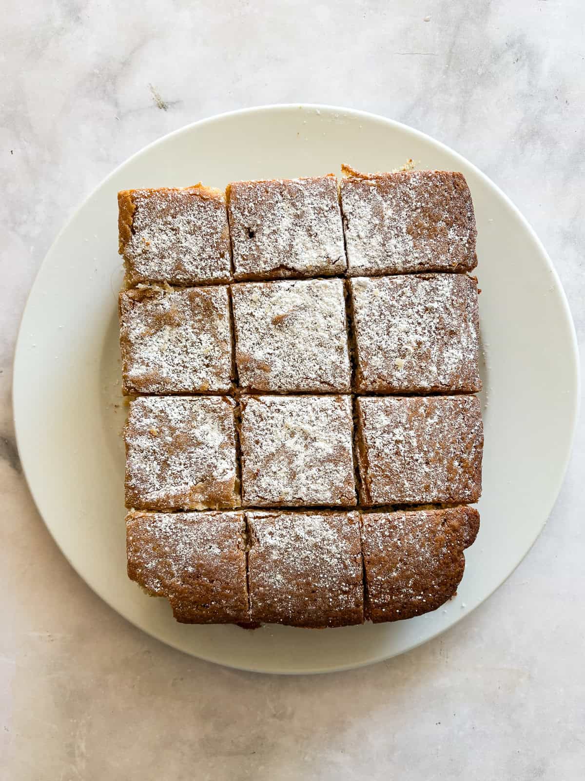 Whip up this one-bowl gluten free snack cake and enjoy with a cup of coffee, or have it waiting on the counter for when the kids come home. A gluten free snack cake on a plate, cut into pieces.
