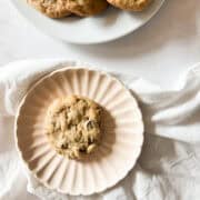 A gluten free tahini chocolate chip cookie on a plate next to a plate of cookies.