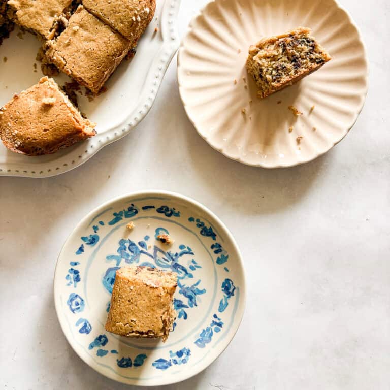 Two pieces of oat flour chocolate chip snack cake on plates next to the cake.