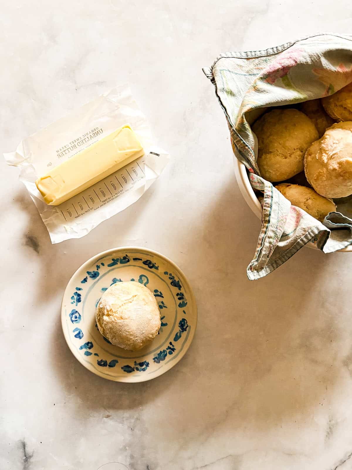 Tender and light soda biscuits need just five simple ingredients and an easy prep method - a keeper of a recipe! A stick of butter, a soda biscuit on a plate, and a bowl of biscuits.