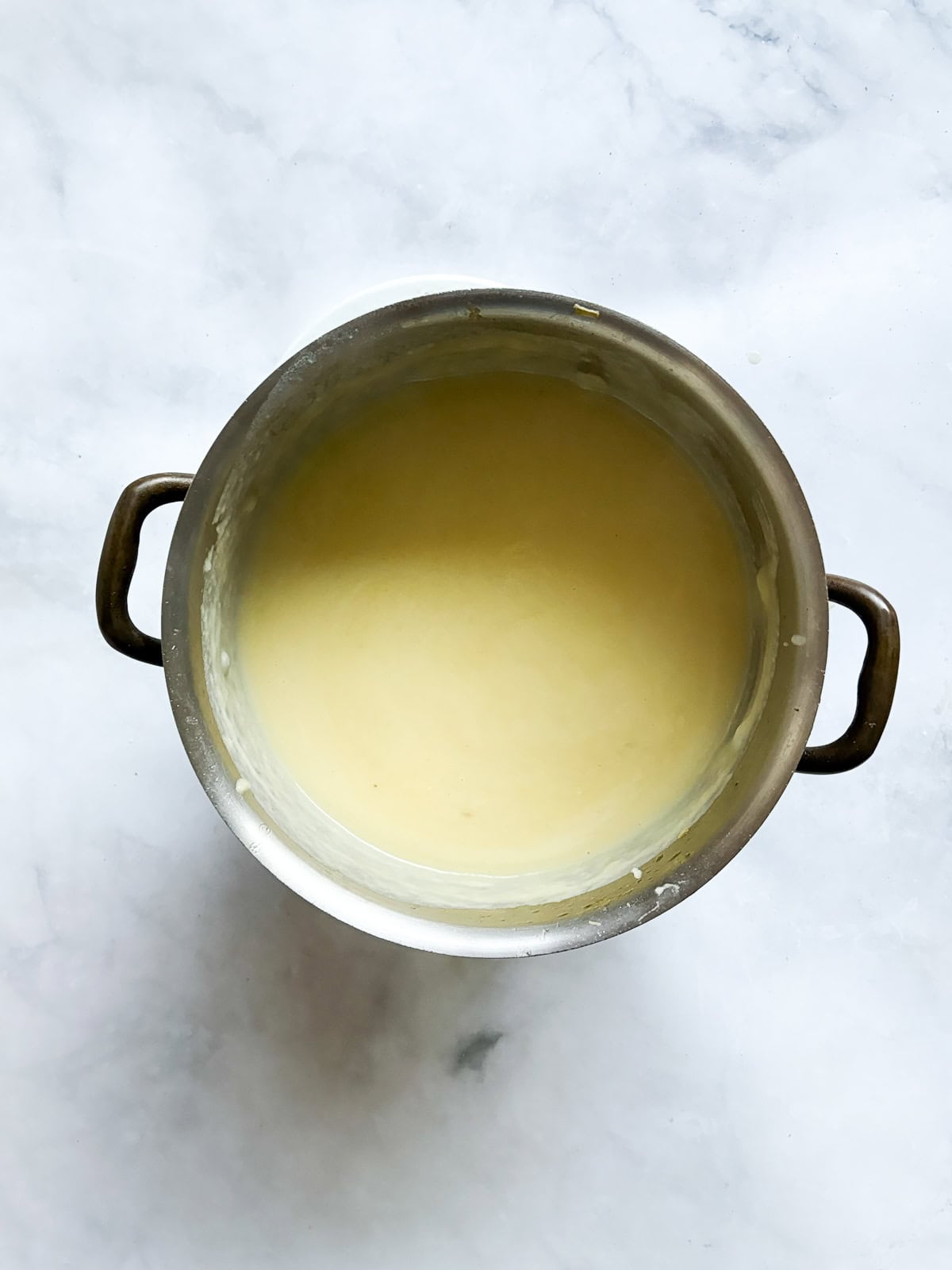 Rich and smooth vegetarian potato leek soup is made from simple ingredients that transform into something deliciously memorable. A pot of pureed vegetable potato leek soup.