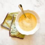 A bowl of vegetarian potato leek soup on a napkin with a spoon.