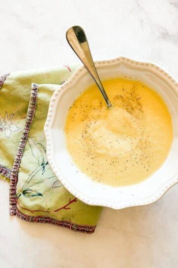 A bowl of vegetarian potato leek soup on a napkin with a spoon.