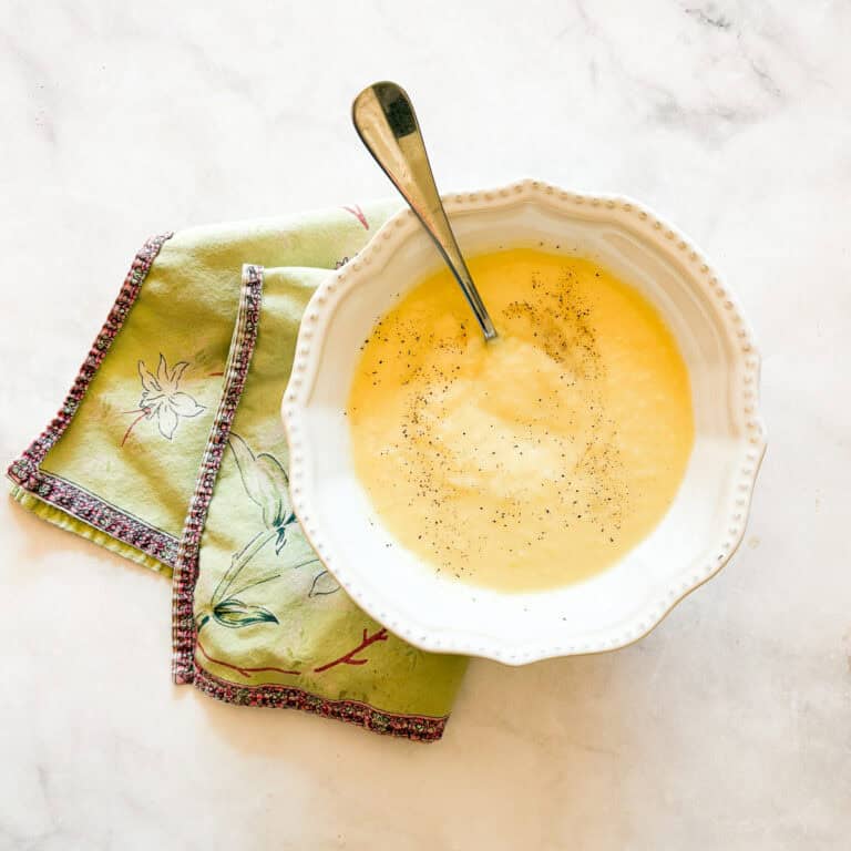A bowl of vegetarian potato leek soup on a napkin with a spoon.