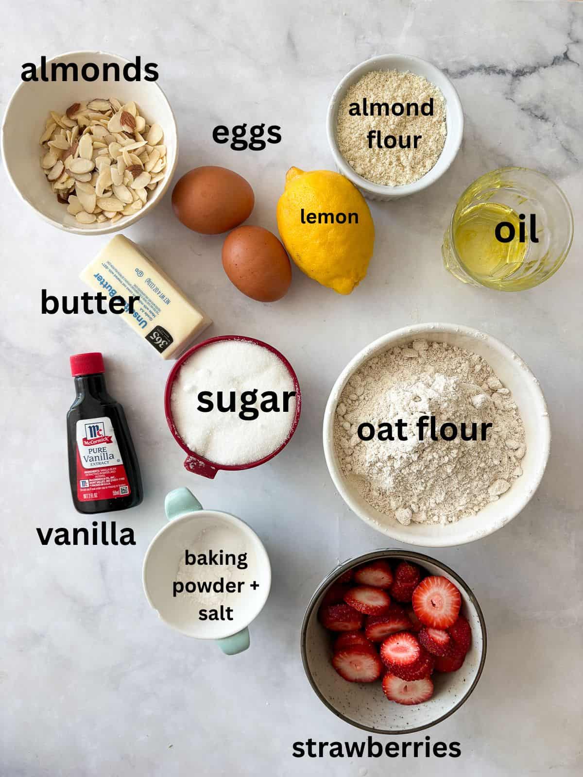 A gorgeous gluten free strawberry almond cake loaded with fresh fruit and topped with toasted almonds and a shower of powdered sugar. Ingredients for gluten free strawberry almond cake are text-labeled.
