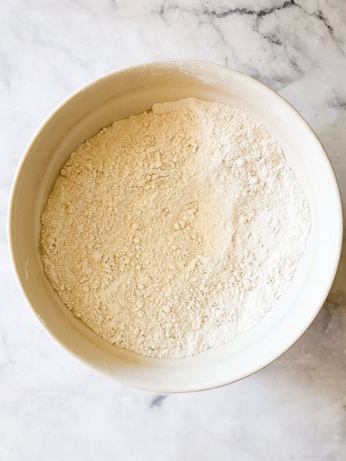 This gum-free, gluten free bread flour recipe is a go-to for breads and pastries of all kinds! Use it 1:1 in your favorite recipes. Different flours are mixed together in a bowl to make homemade gluten free bread flour.