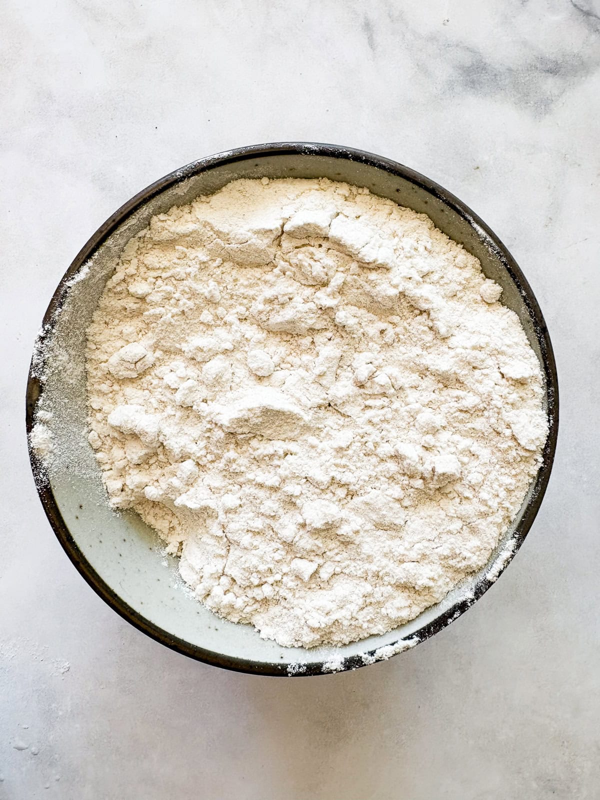This gum-free, gluten free bread flour recipe is a go-to for breads and pastries of all kinds! Use it 1:1 in your favorite recipes. A small bowl holds a measure of gluten free bread flour.