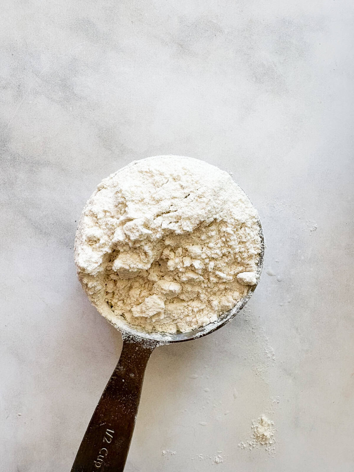 This gum-free, gluten free bread flour recipe is a go-to for breads and pastries of all kinds! Use it 1:1 in your favorite recipes. A measuring cup holds gluten free bread flour.