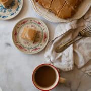 Pieces of gluten free caramel cake on plates with the cake nearby and a cup of coffee.