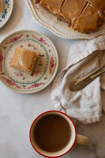Pieces of gluten free caramel cake on plates with the cake nearby and a cup of coffee.