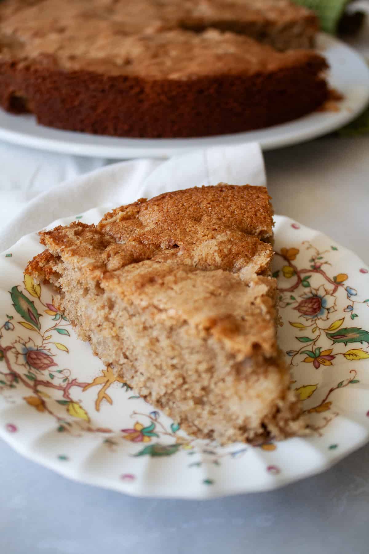 A soft and sweet gluten free Irish apple cake that's inspired by a traditional Irish recipe. Delicious plain, it can be served warm or cold. A big slice of gluten free Irish apple cake on a decorative plate.
