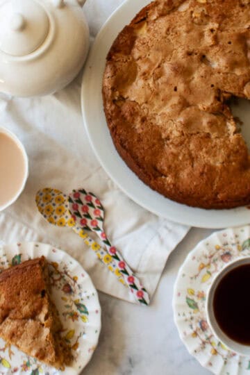 A gluten free Irish apple cake with a tea pot and cups of tea.