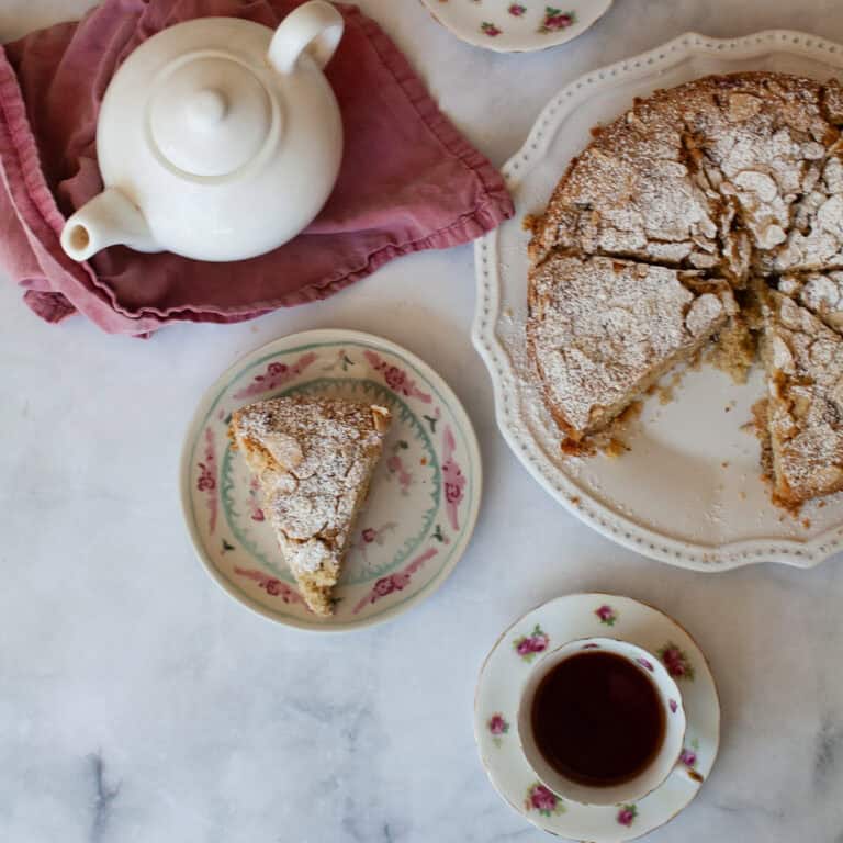 A pot of tea, a cup of tea, and a gluten free strawberry almond cake.