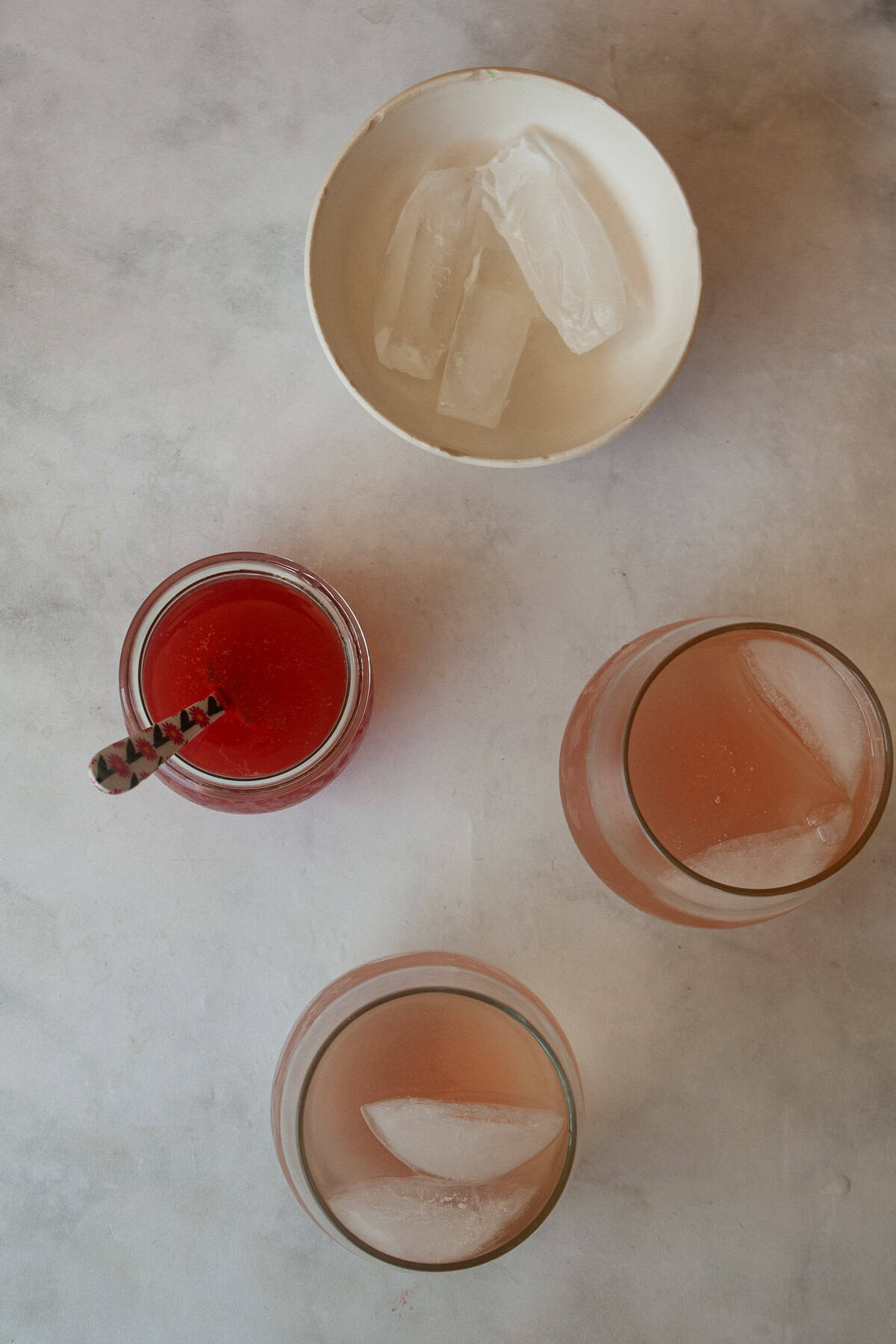 For a gorgeous twist on a classic, stir homemade rhubarb syrup into good gin and bubbly tonic water for a refreshing cocktail. Glasses of rhubarb gin and tonic, ice, and rhubarb syrup.