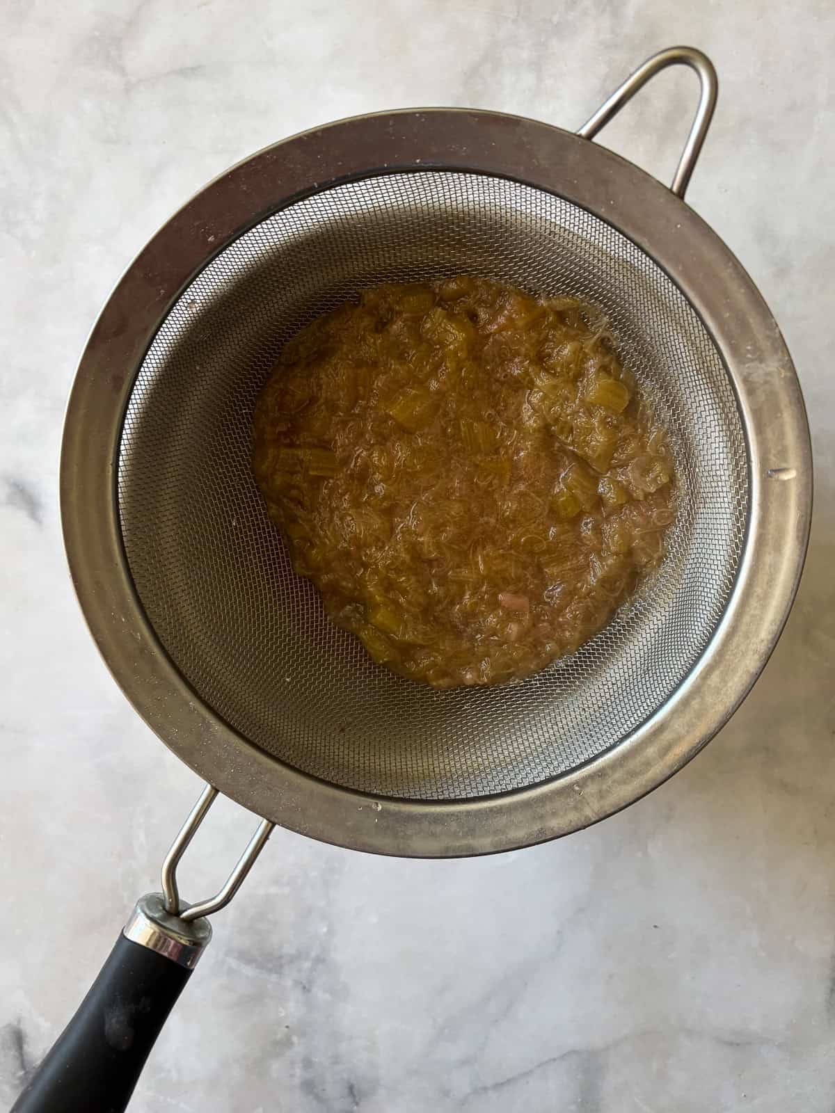 Gorgeously hued and perfectly sweet-tart, rhubarb simple syrup is a delightful addition to all sorts of drinks (and more). Rhubarb simple syrup strained out into a bowl.