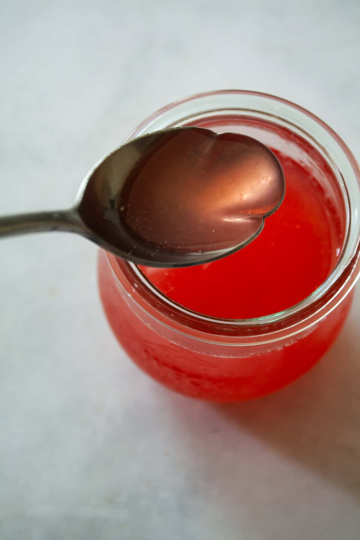Gorgeously hued and perfectly sweet-tart, rhubarb simple syrup is a delightful addition to all sorts of drinks (and more). A spoon lifts out a bit of rhubarb simple syrup from a jar.