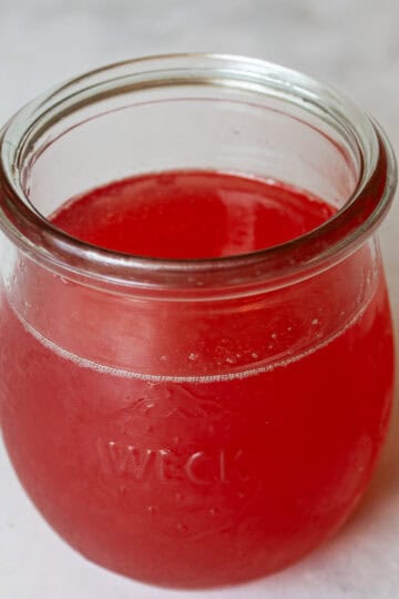 A brightly colored jar of rhubarb simple syrup.