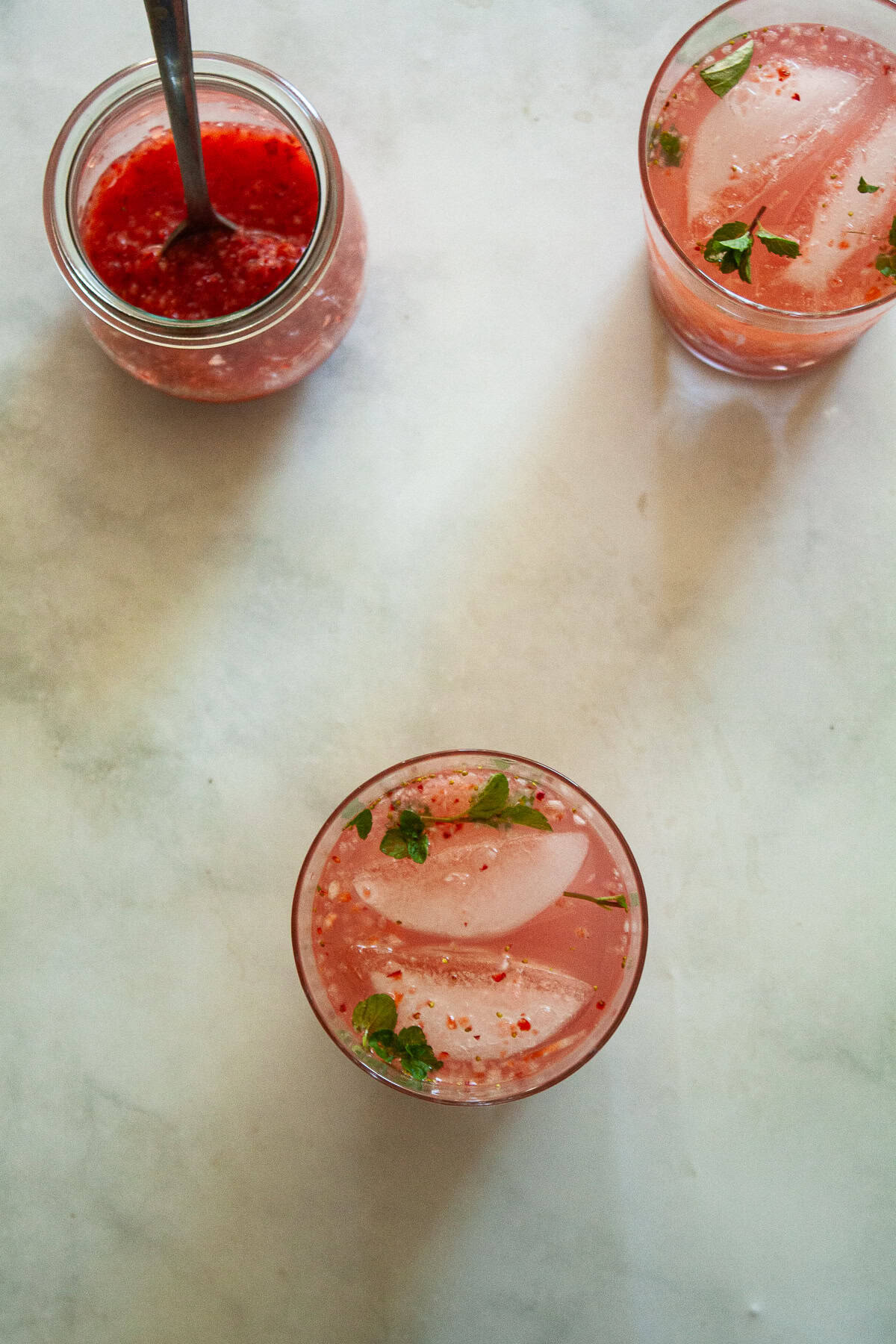 This beautiful strawberry cocktail can be made with or without gin, and is packed with fresh strawberries and mint! Two strawberry cocktails and a jar of strawberry puree.