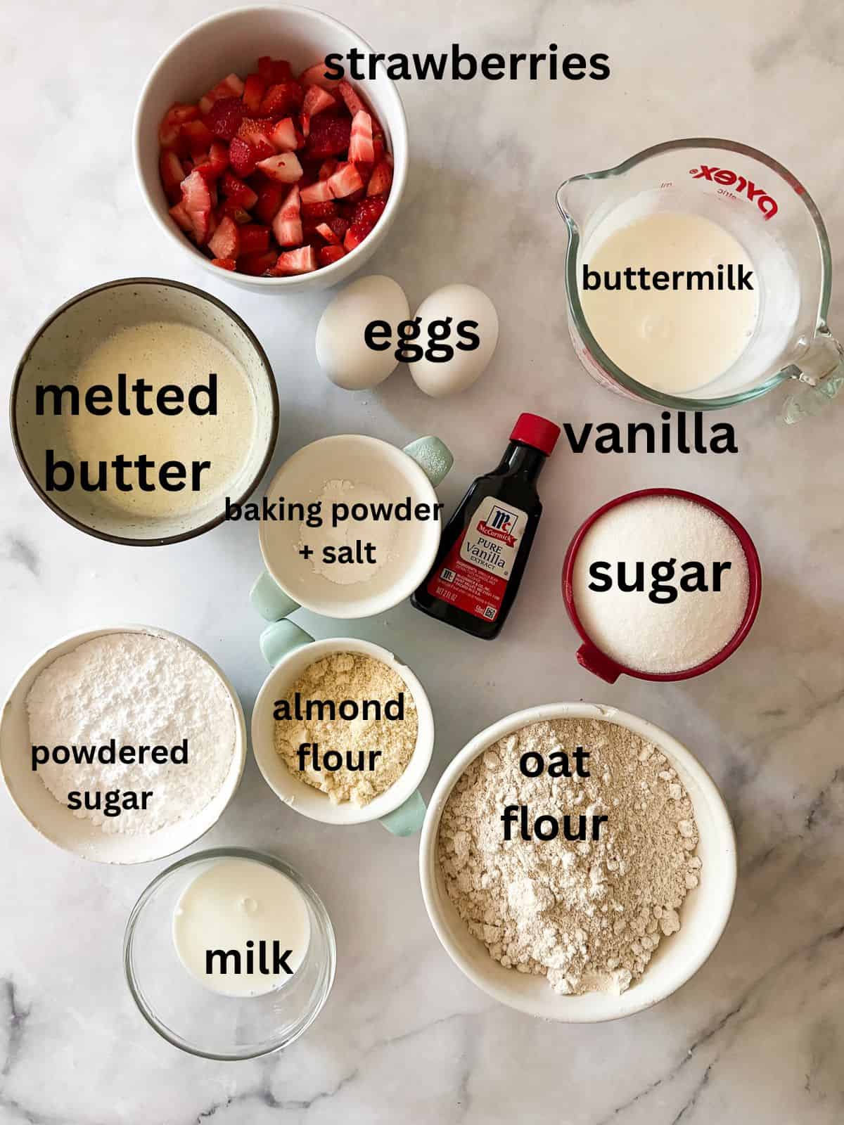 A tender, fruit-flecked gluten-free strawberry loaf cake topped with a simple and sweet vanilla glaze. The best summery bake! Ingredients for gluten free strawberry loaf cake are text-labeled.