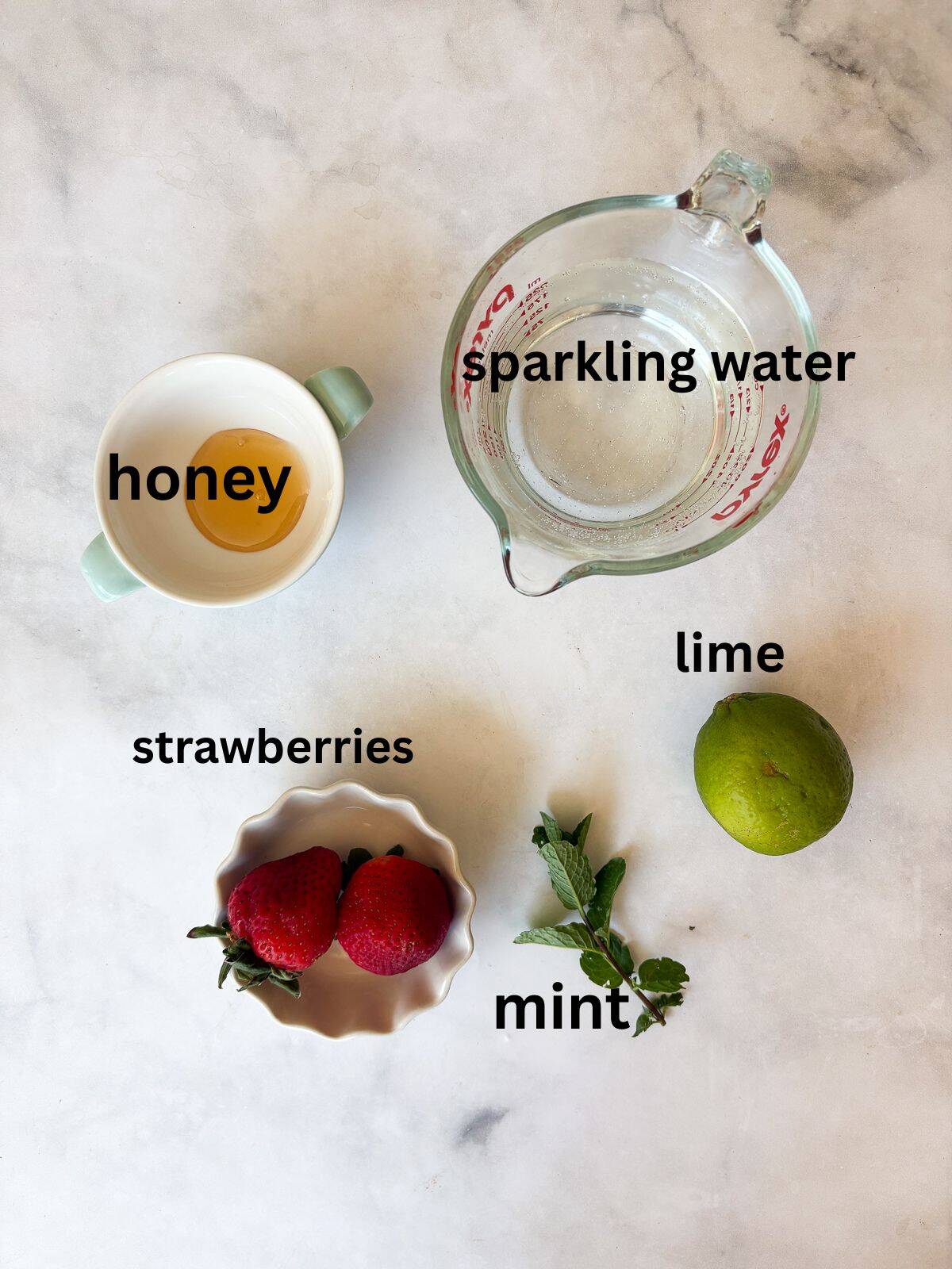 This strawberry mocktail is a not-too-sweet, non-alcoholic drink featuring juicy strawberries muddled with honey, lime, and mint. Ingredients for a strawberry mocktail are text-labeled.