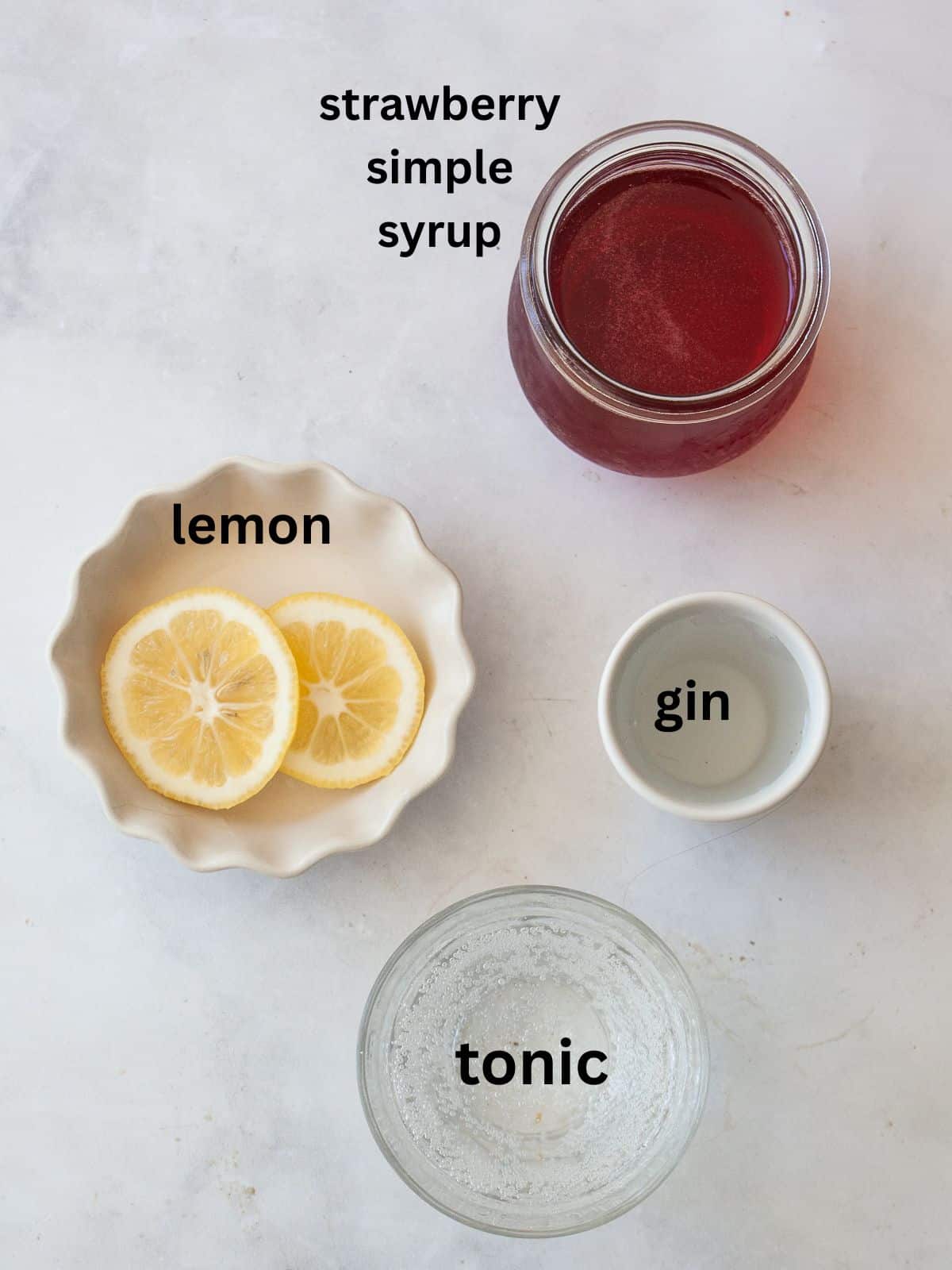 Enjoy this strawberry gin and tonic all summer long! A fruit twist on a classic, sweet strawberry syrup elevates this familiar cocktail. Ingredients for strawberry gin and tonic are text-labeled.