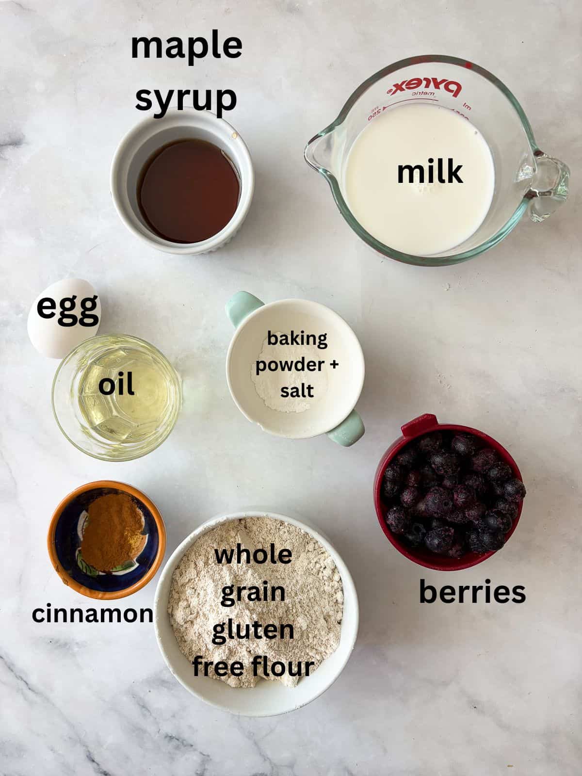 These one-bowl gluten-free berry muffins are made with your choice of whole grain flour and are sweetened just with maple syrup! Ingredients for gluten free berry muffins are text-labeled.