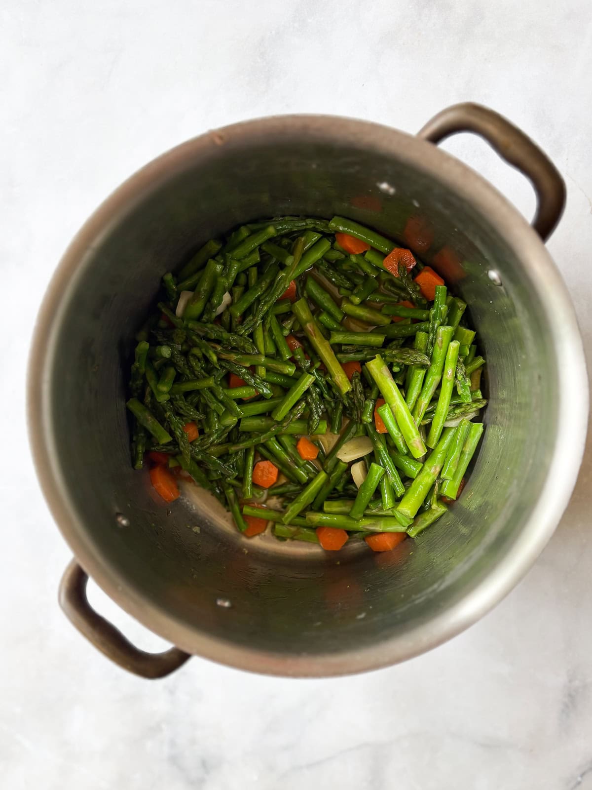 Creamy, vegan asparagus and spinach soup is made with minimal ingredients to create a velvety, nourishing soup that's always welcome. Asparagus is added to the pot.