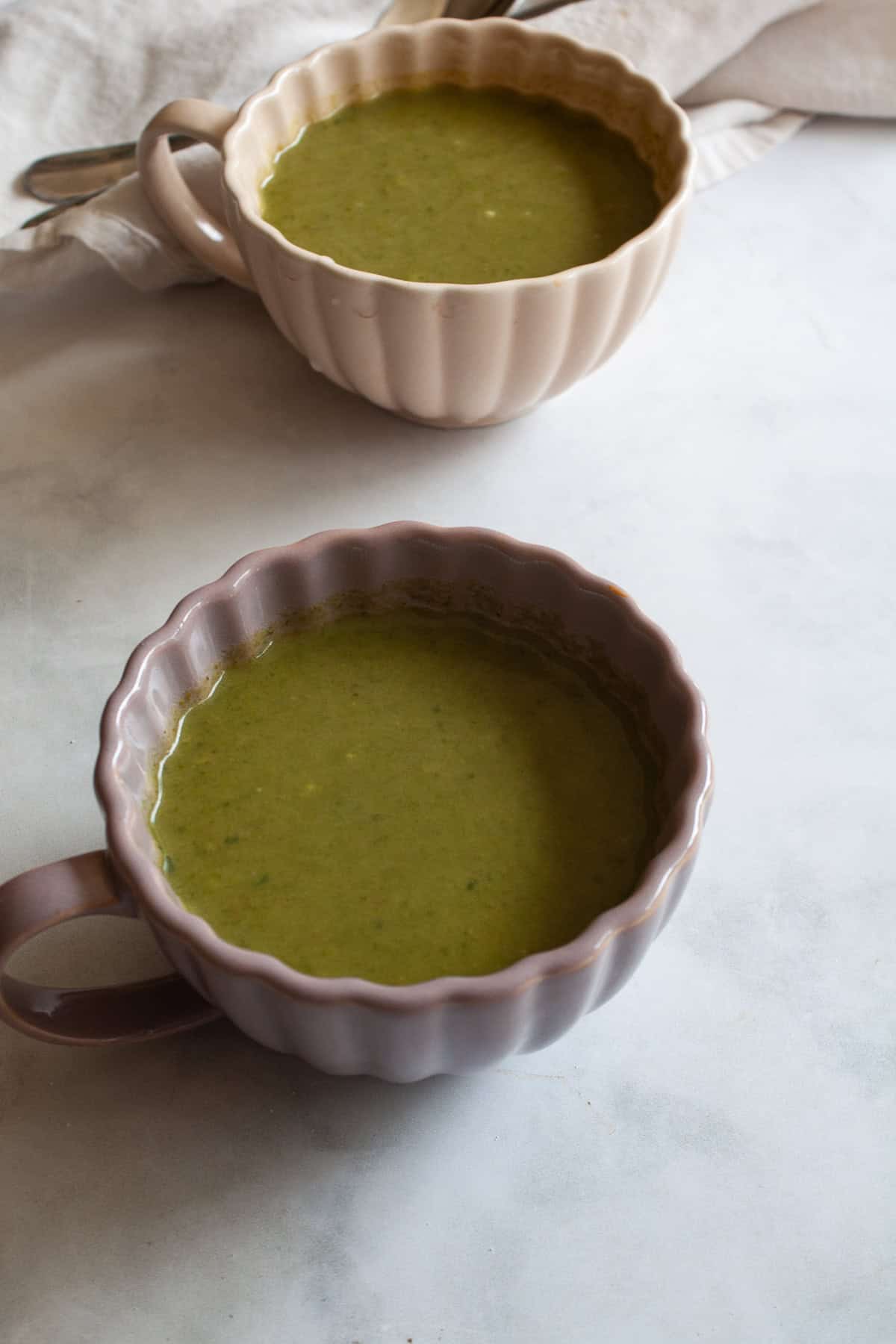 Creamy, vegan asparagus and spinach soup is made with minimal ingredients to create a velvety, nourishing soup that's always welcome. Two cups of asparagus and spinach soup.