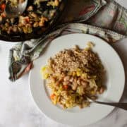 A skillet with white bean and cabbage stir fry next to a plate of stir fry.