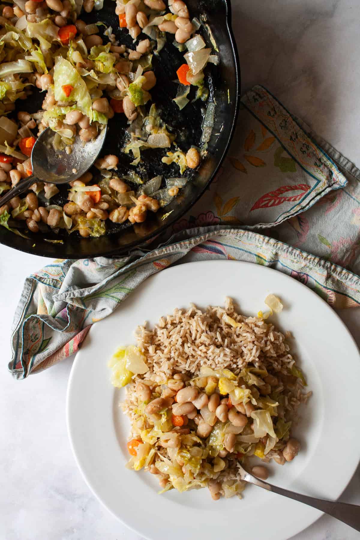 Quick, nourishing, and packed with savory veggies, tender cabbage, and hearty beans, this cabbage stir fry is super satisfying. Vegetarian! A skillet with white bean and cabbage stir fry next to a plate of stir fry.