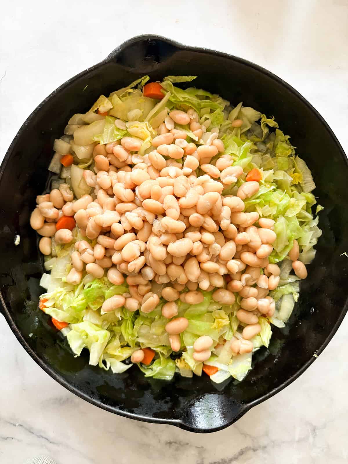 Quick, nourishing, and packed with savory veggies, tender cabbage, and hearty beans, this cabbage stir fry is super satisfying. Vegetarian! Beans are added to the skillet.