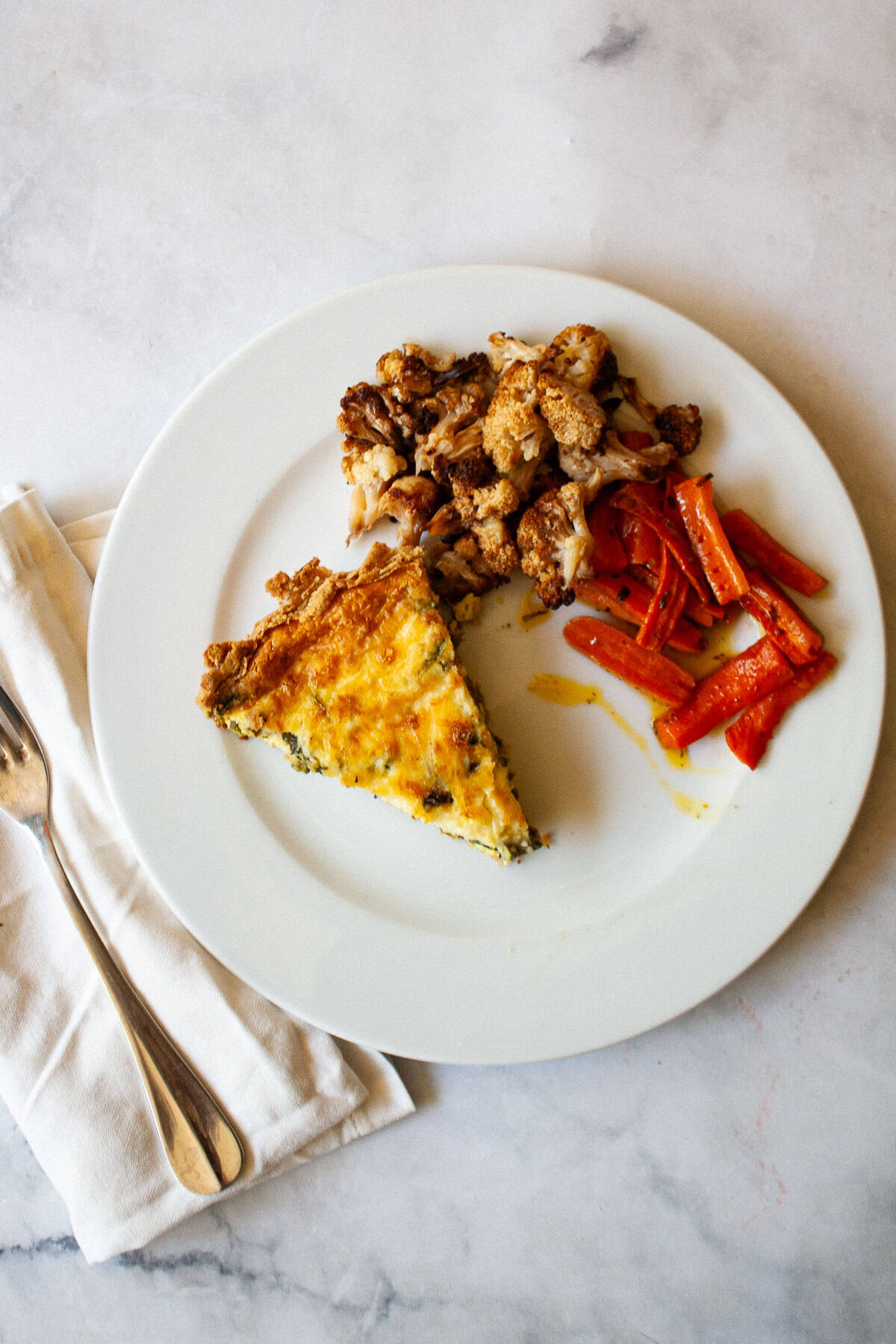 A plate with a slice of gluten free asparagus and a side of cauliflower and carrots.