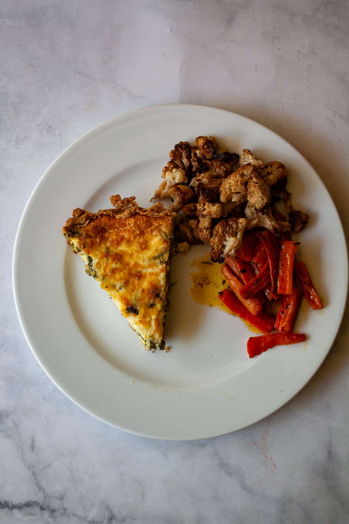 This gluten free asparagus quiche is packed with springy asparagus and salty parmesan cheese to make a wonderful brunch or dinner dish! A slice of gluten free asparagus quiche on a plate with vegetables.