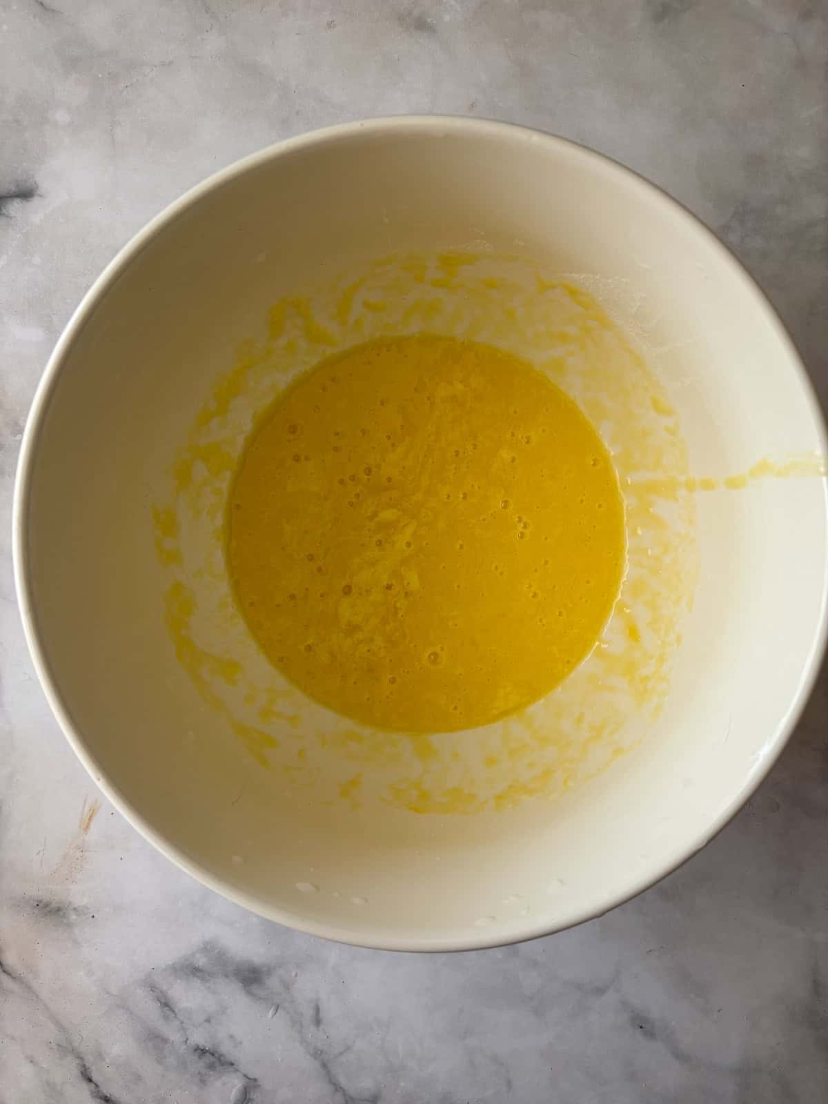 Eggs, sugar, and yogurt are whisked together in a bowl.